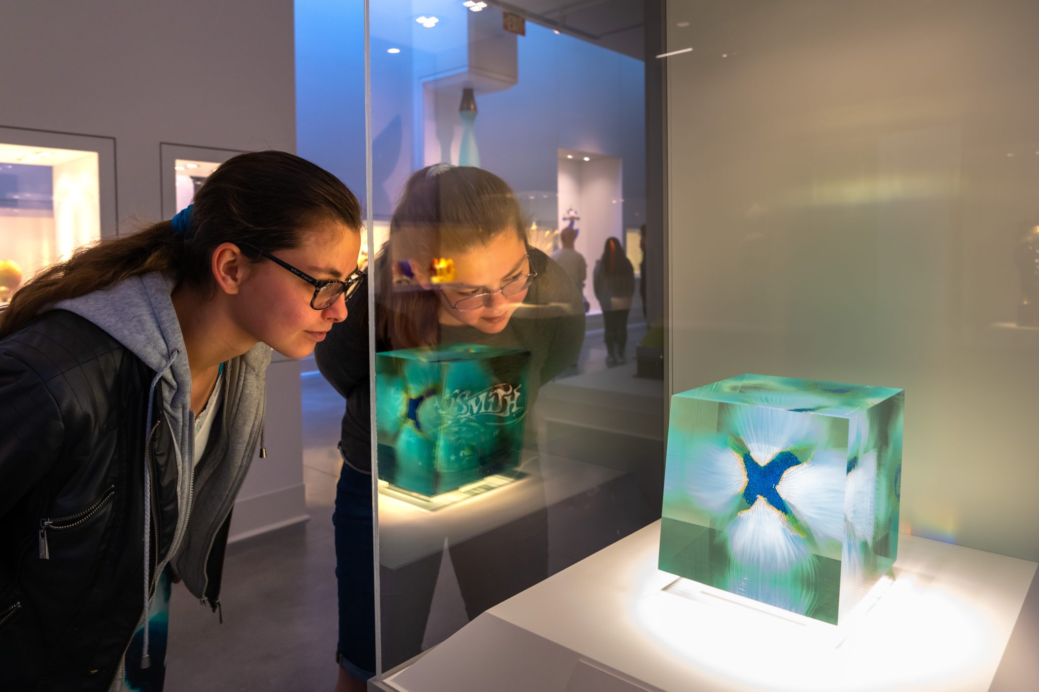 A student admiring a glass sculpture at the Flint Institute of Arts